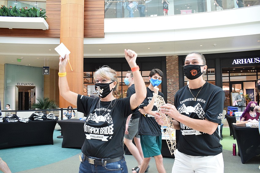 Wendy Kuhns, an engineering teacher at Sarasota High School, and Staci LaPorte, a math teacher at Suncoast Polytechnical High School, celebrate after Kuhns' bridge held 25 poundings before breaking.