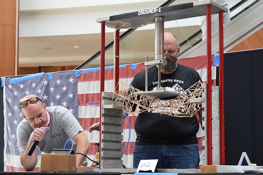Volunteers Ben Quartermaine and Mike Elfers keep track of how many pounds the bridge holds before cracking.