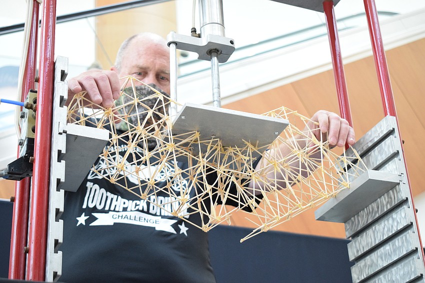 Volunteer Mike Elfers removes Sarasota High School sophomore Om Patel's bridge from the crusher. It held 40 pounds of pressure.