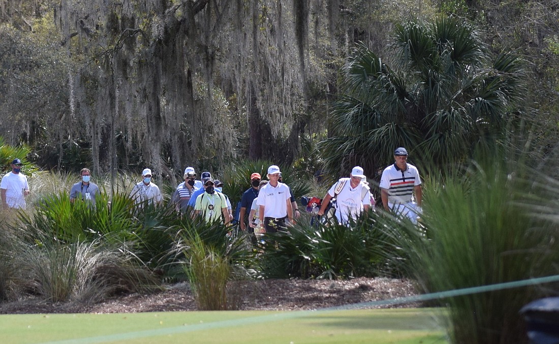 Bryson DeChambeau leads some invited fans up to the ninth fairway at The Concession.