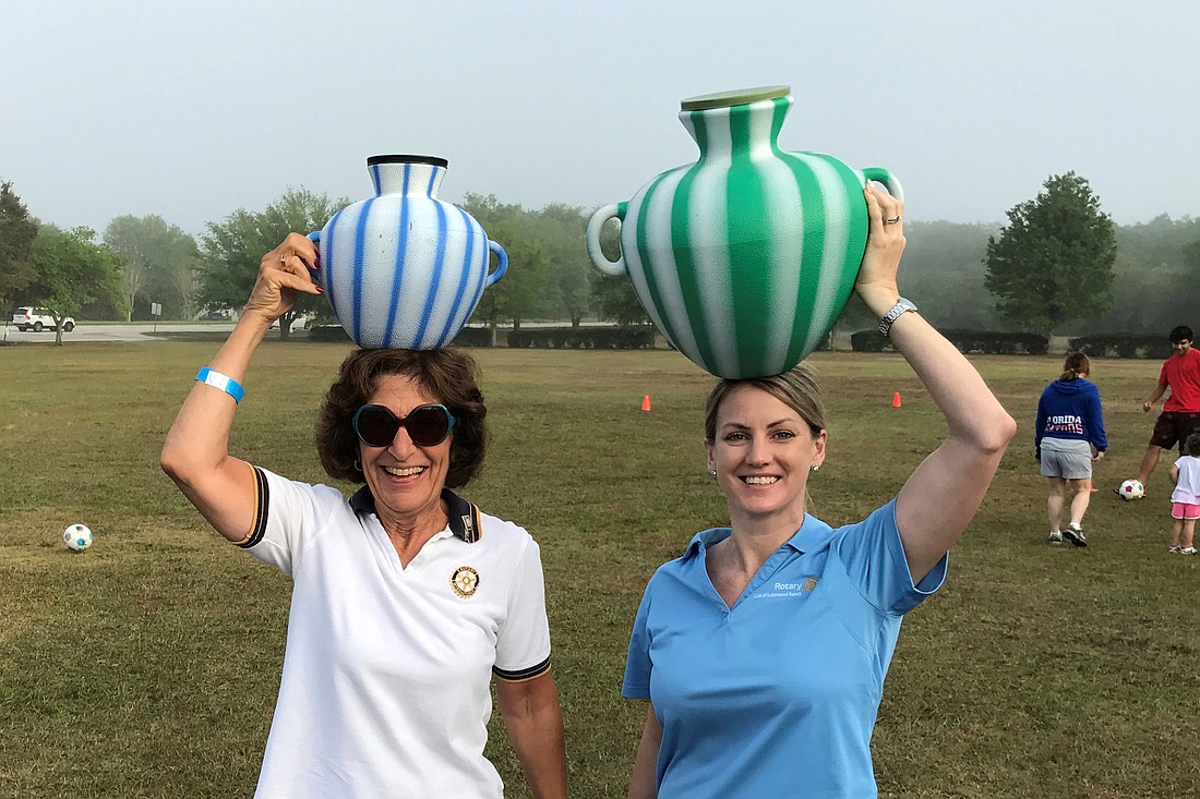 Judy Berlow and Susan Courter hold jugs of water. The Walk for Water fundraiser allows participants to imagine what it would be like to carry a bucket of water the same distance mothers and children would walk to access water.