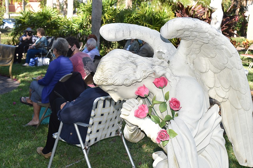 Members set up chairs around the planters and statues in the garden.