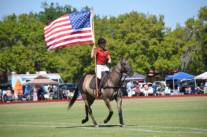 Paige Lautzenheiser, the director of operations for the Sarasota Polo Club, presents the colors.