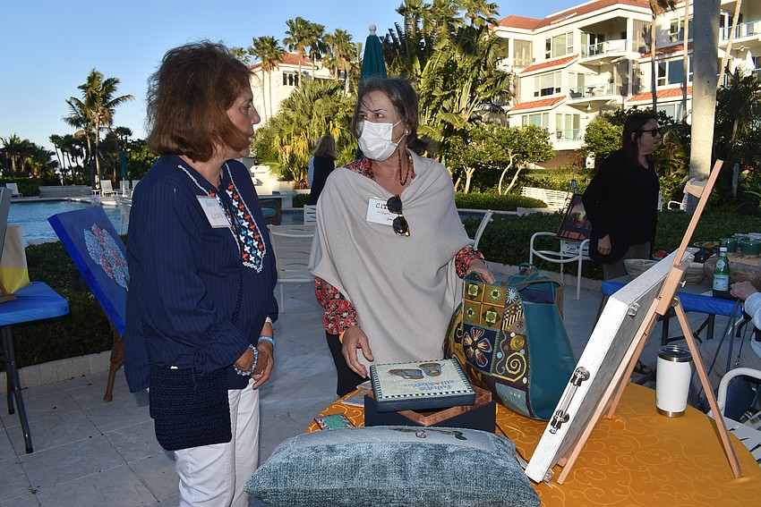 Clare Villari, right, shows her needlepoint to Nancy Lutzke.