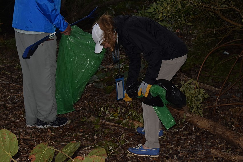Mike Haycock holds a bag open while Lyn Haycock grabs trash.