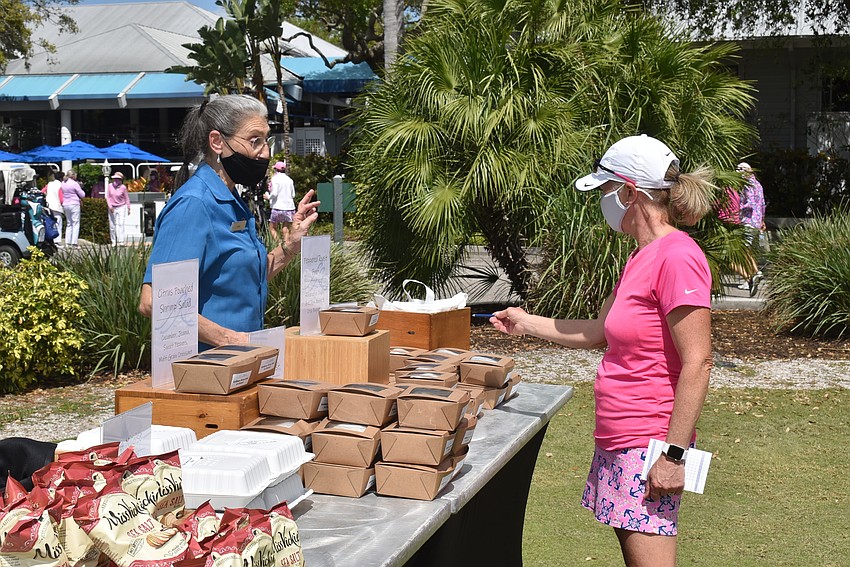 Louise Berg, right, selects her lunch from the table of to-go containers.