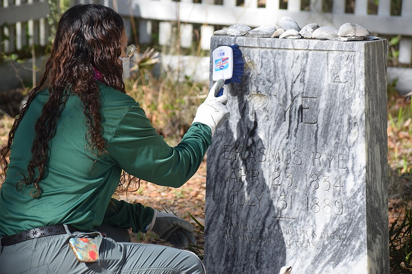 Sara Alvarez, an eduction and volunteer specialist for Manatee County, gently scrubs a headstone.