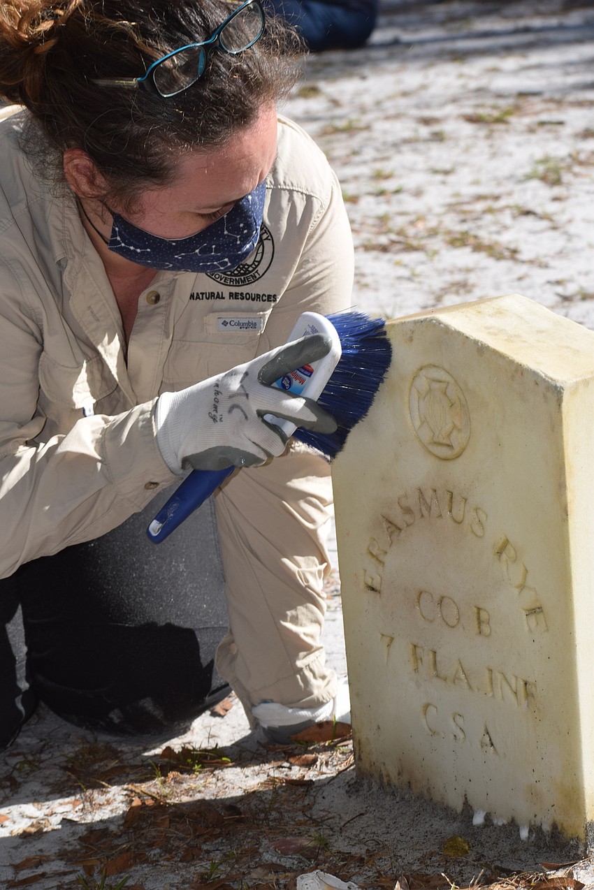 Michelle Leahy, a Manatee County volunteer specialist for Parks and Natural Resources, works on a headstone during the Rye Cemetery Preservation and Beautification project.