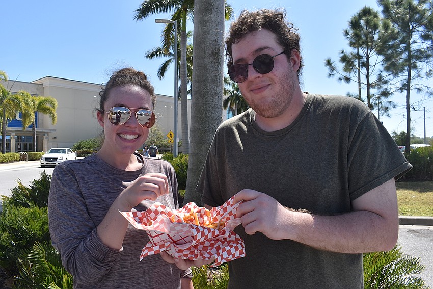 Sarasota residents Erika Miller and John Quartuccio share bacon cheese fries from the Currywurst Truck. Quartuccio also enjoyed a bratwurst roll from the truck.