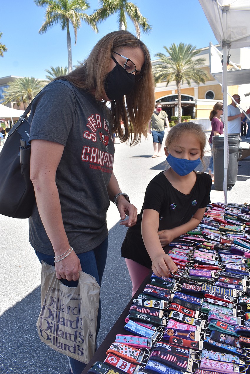 Sarasota residents Jeanette Cole and Mylah Cole, 6, look at key fobs from the Ally Binky Shop. Jeanette ended up selecting a Starbucks key fob, while Mylah chose a lizard bracelet.