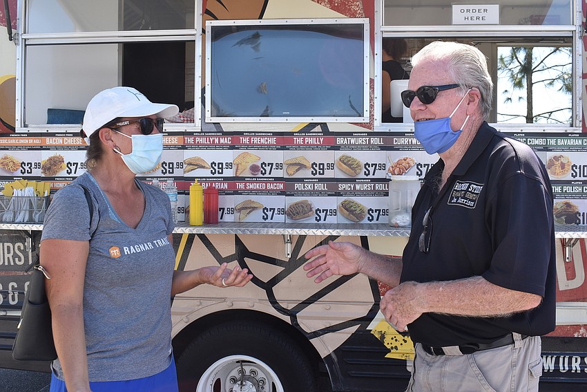 Rockman Studio owner Joe Morrison speaks with Sarasota resident Sonja Dickey in front of the Currywurst Truck. Dickey said she came to the market for the food and jewelry, such as that sold by Morrison.