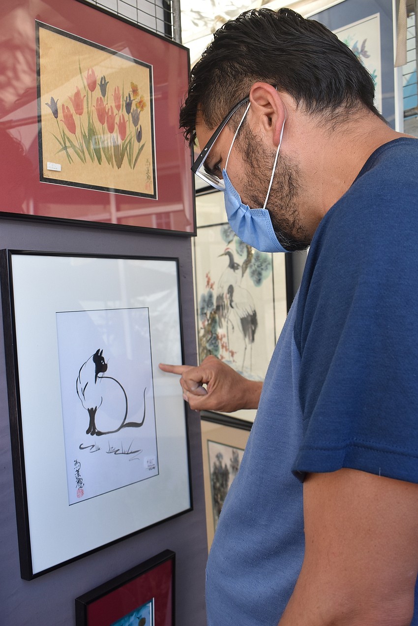 St. Petersburg resident Jose Vizcarra admires a Chinese brush painting created by Wisconsin-based artist Charlotte Fung Miller. Vizcarra was also an artist at the festival.