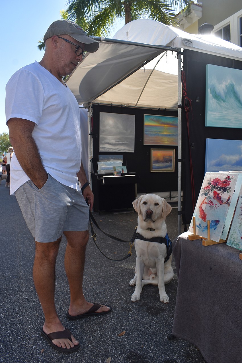 Lakewood Ranch resident Perry Costales takes 4-year-old yellow Labrador retriever Vincent for a walk through the festival. Costales said he came to see beautiful paintings and enjoy the warm, sunny weather.