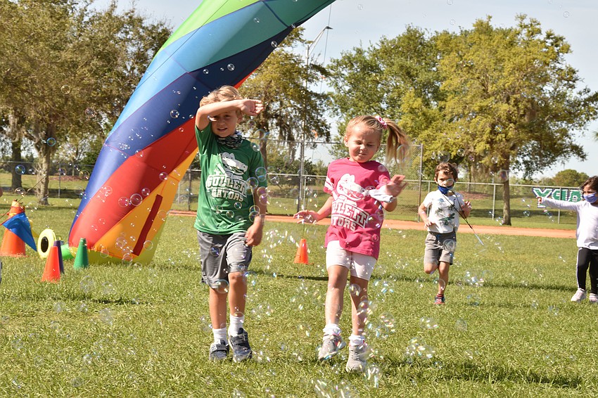 Kindergartners Hank Hausfeld and Blaire Wilson run through bubbles after passing the rainbow arch. Courtesy photo.