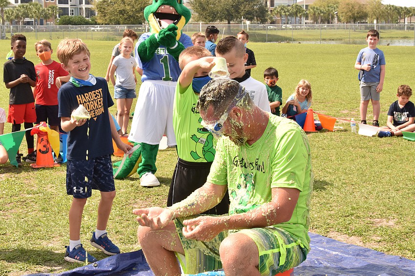 Second grader Drew Levine laughs as second grader Sullivan Shea pours slime on the head of Todd Richardson, who is the principal.
