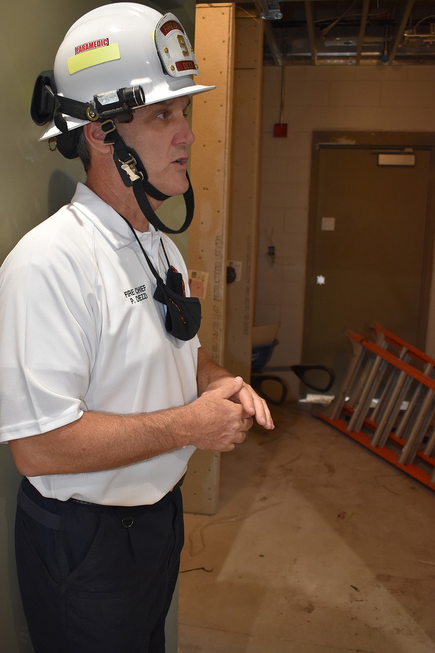 Fire Chief Paul Dezzi demonstrates how the new Fire Station 92’s red, yellow and green decontamination system will work. Firefighters will take two showers before they can return inside of the building.