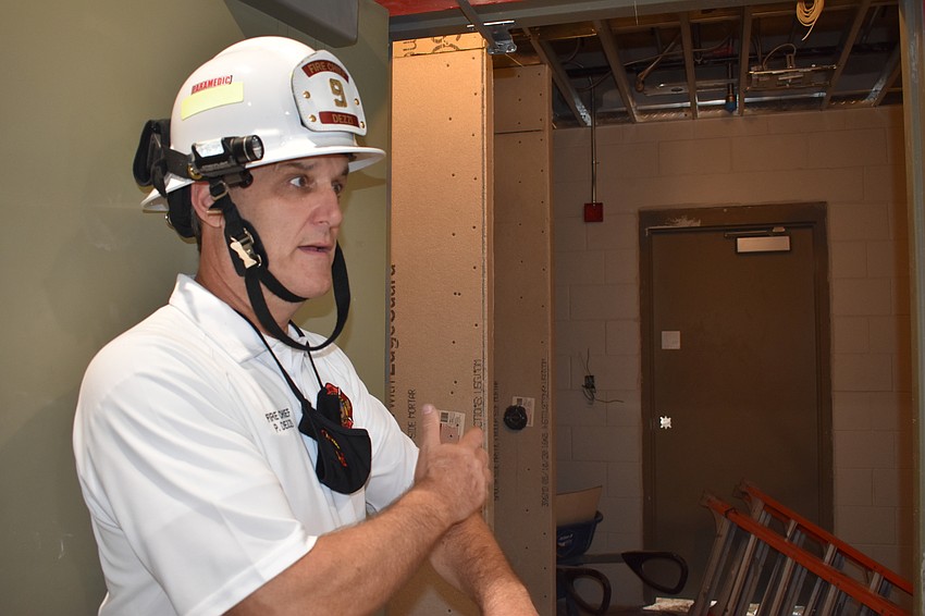 Fire Chief Paul Dezzi demonstrates how the new Fire Station 92’s red, yellow and green decontamination system will work. Firefighters will take two showers before they can return inside of the building.