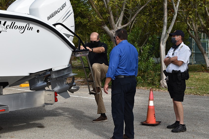 Town Manager Tom Harmer (far left) climbs aboard the police department's new boat.