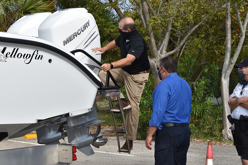Town Manager Tom Harmer (far left) climbs aboard the police department's new boat.