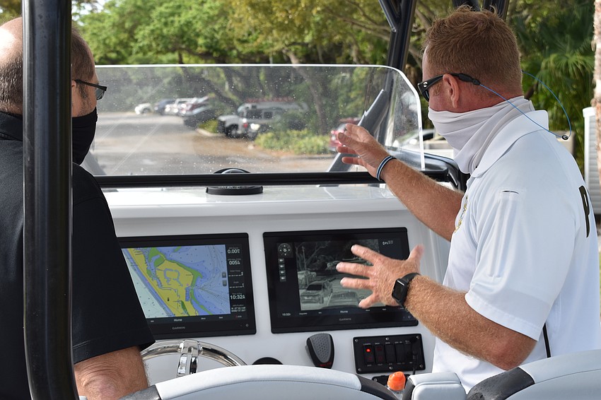 Marine patrol officer Joshua Connors (right) demonstrates to Town Manager Tom Harmer (left) how the two Garmin displays are used on the police department's new boat.