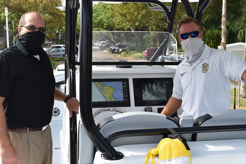 Town Manager Tom Harmer (left) and marine patrol officer Joshua Connors (right) pose for a photo on the police department's new boat.