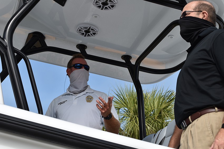 Marine patrol officer Joshua Connors (left) demonstrates to Town Manager Tom Harmer (right) how the two Garmin displays are used on the police department's new boat.