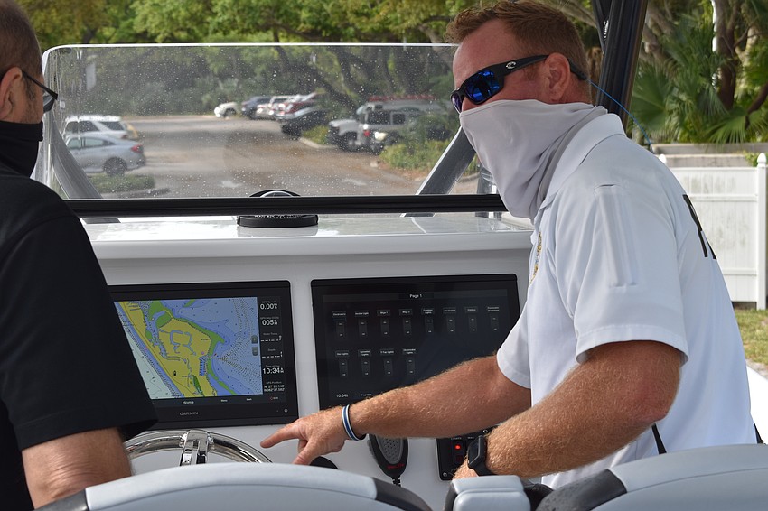Marine patrol officer Joshua Connors (right) demonstrates to Town Manager Tom Harmer (left) how the two Garmin displays are used on the police department's new boat.