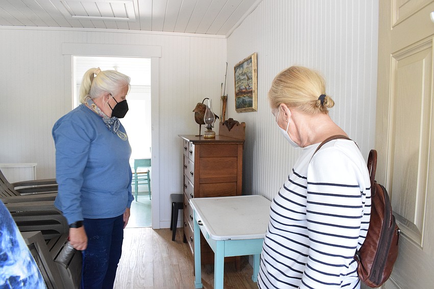 Denise Kleiner, the operator of Jiggs Landing, shows Lakewood Ranch's Suzanne MacDonald and Francesca Tulski the furniture in the replica cabin.