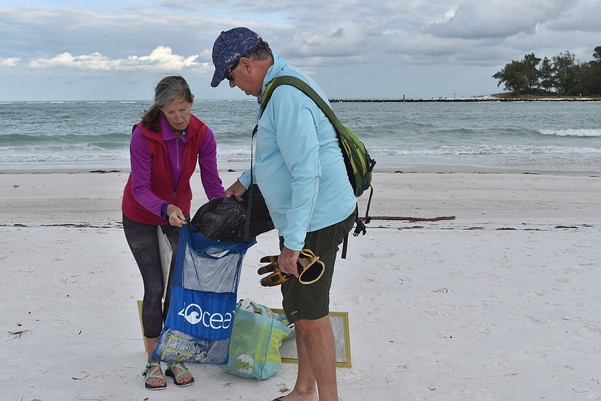 Cyndi Seamon holds open Brian Maddox's bag as he stuffs a bag into it.