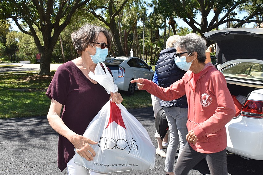 Mac Spitzer, right, calls over more volunteers to help unload a packed car as Karen Gary takes a bag to a waiting car.