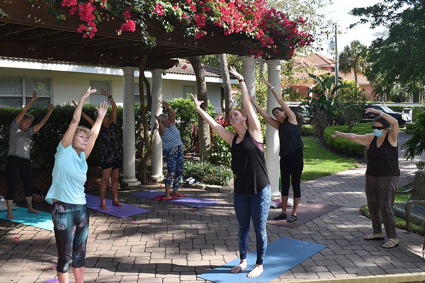 Marj Kirchner, left, tilts as she stretches towards the sky.