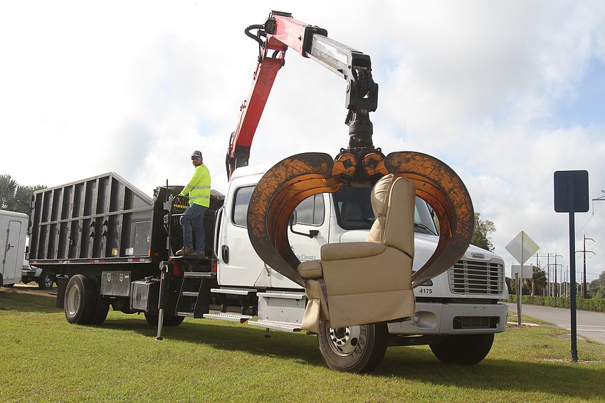 Sarasota County employees manage a grapple truck.