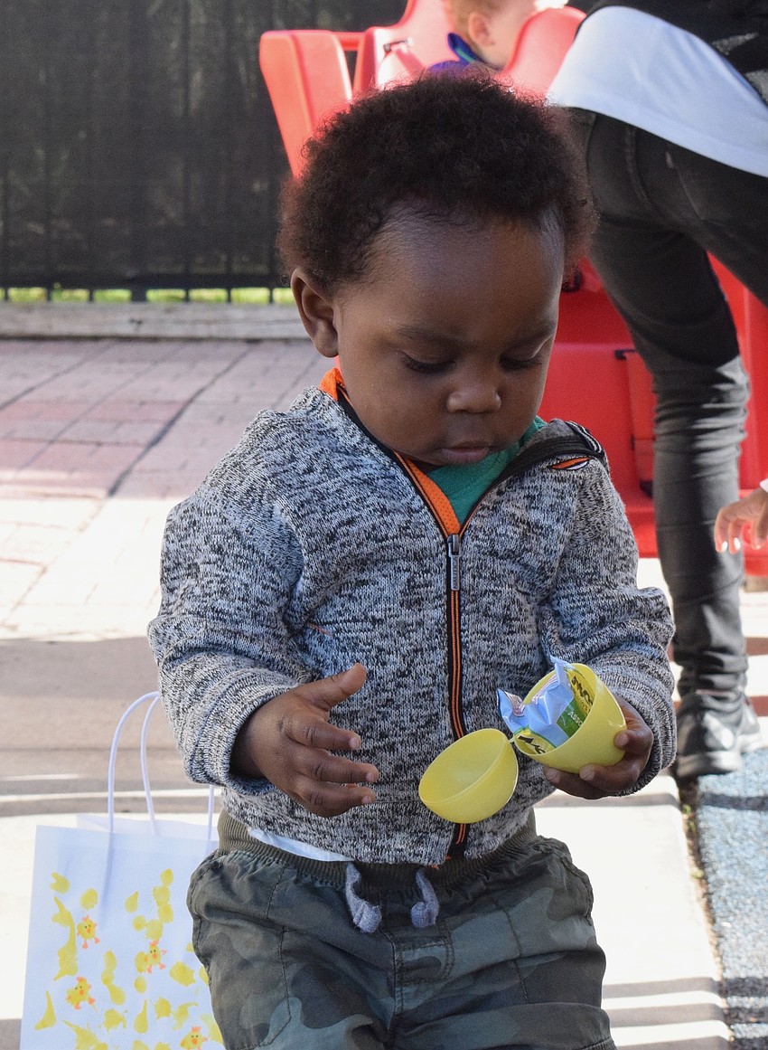 Acai Griffin, who is 1 year old, takes a peek at what's inside some of the eggs he's collecting in the egg hunt.