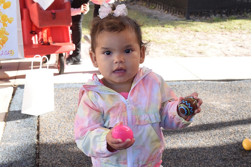 Pynelopee Redmond, who is 1 year old, holds the eggs she collected together before putting them in her bag.