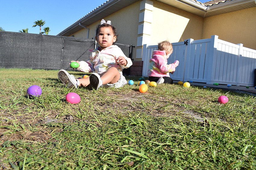Pynelopee Redmond and Gwendolyn Lash, who are both 1 year olds, take a break from collecting eggs during their egg hunt.