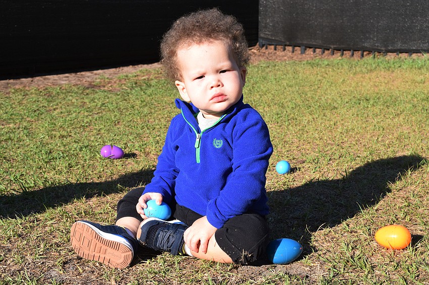 Bennett Drew, who is 1, soaks in some sun while being surrounded by eggs during his class' Easter egg hunt.