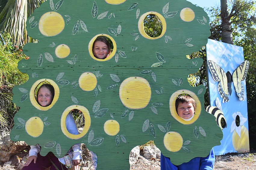 Ruskin resident Aspen Pilant, 10, and Palmetto residents Mylee Gullett, 12, and Bryan Gullett, 10, pose at the orange tree photo station. Pilant and Mylee Gullett enjoyed finding bracelets, while Bryan Gullett loved the ice cream.