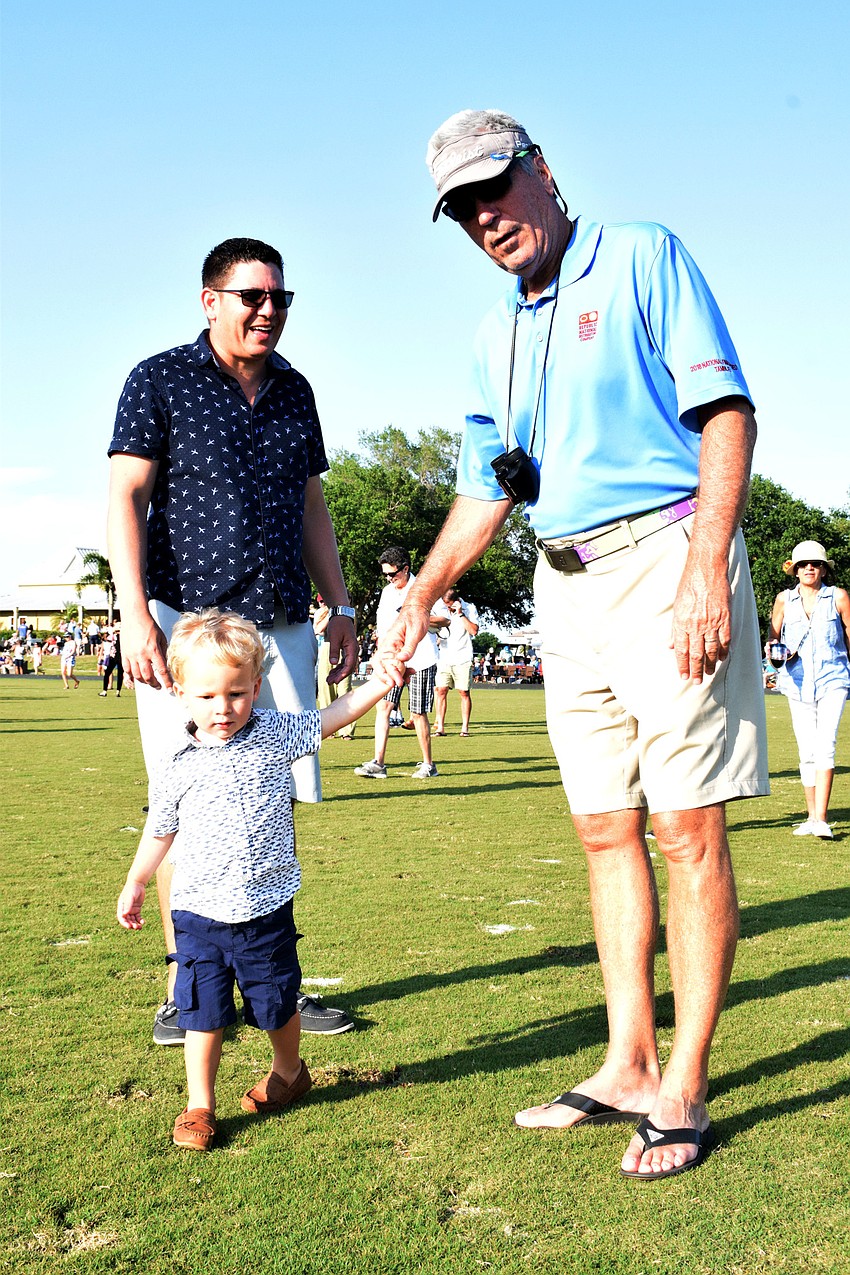 Fort Lauderdale's Danny Pfaadt helps his 2-year-old son Bradlee Pfaadt stomp out divots with his dad Allen Pfaadt, who lives in Lakewood Ranch.