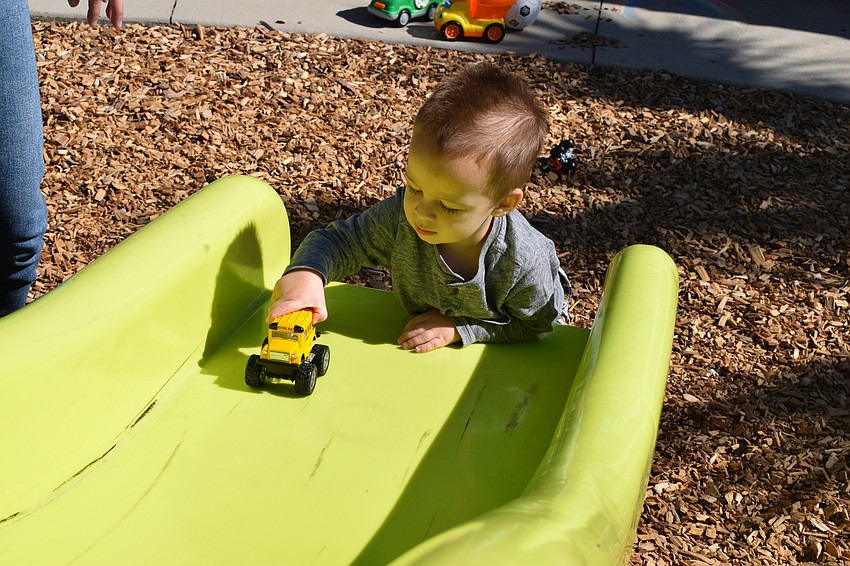 Harmony's Jack Hall, who is 20 months old, pushes his school bus up the slide to see how far it'll go before sliding back down.