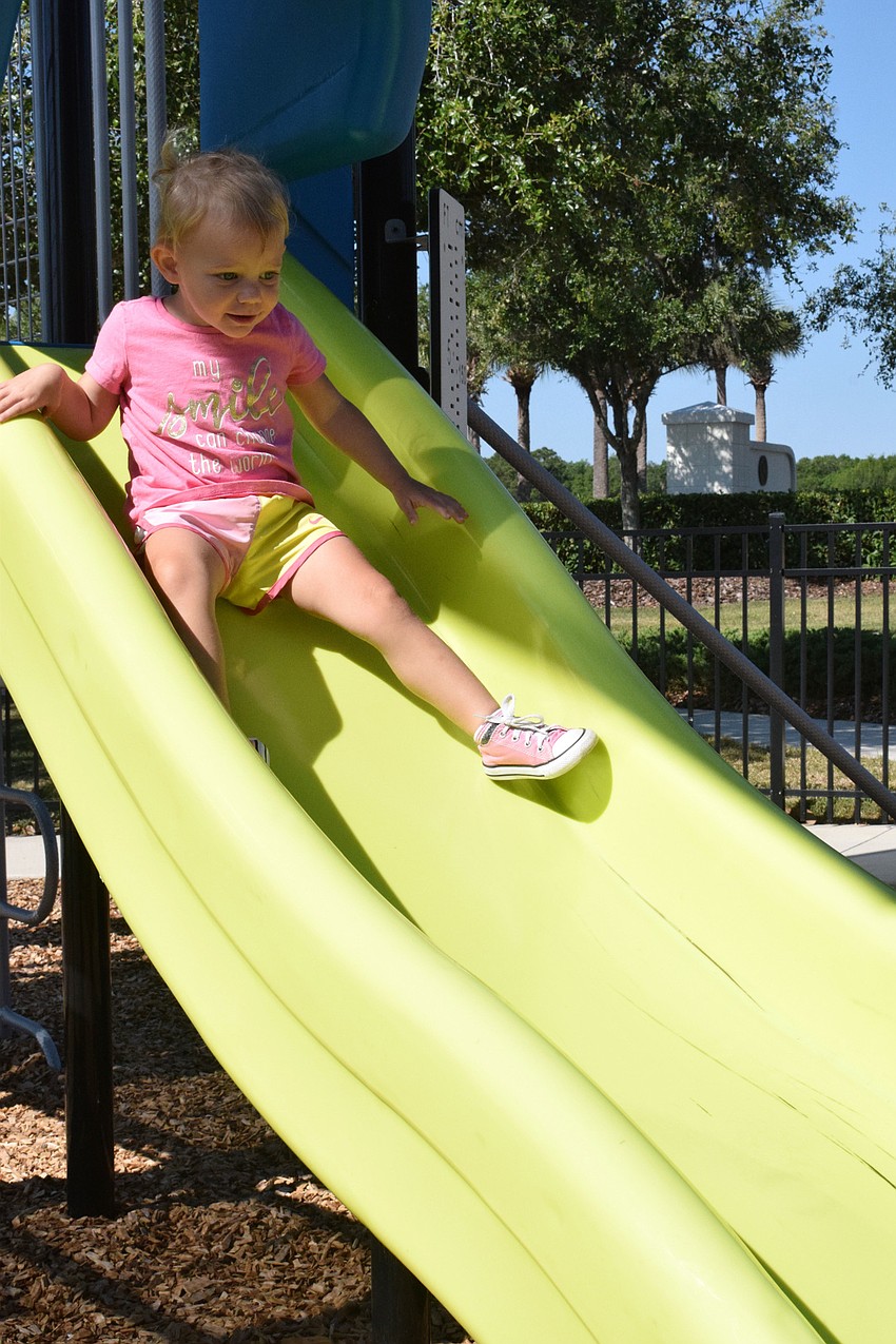 Harmony's Josie McComas, who is 2 years old, laughs while going down the slide.