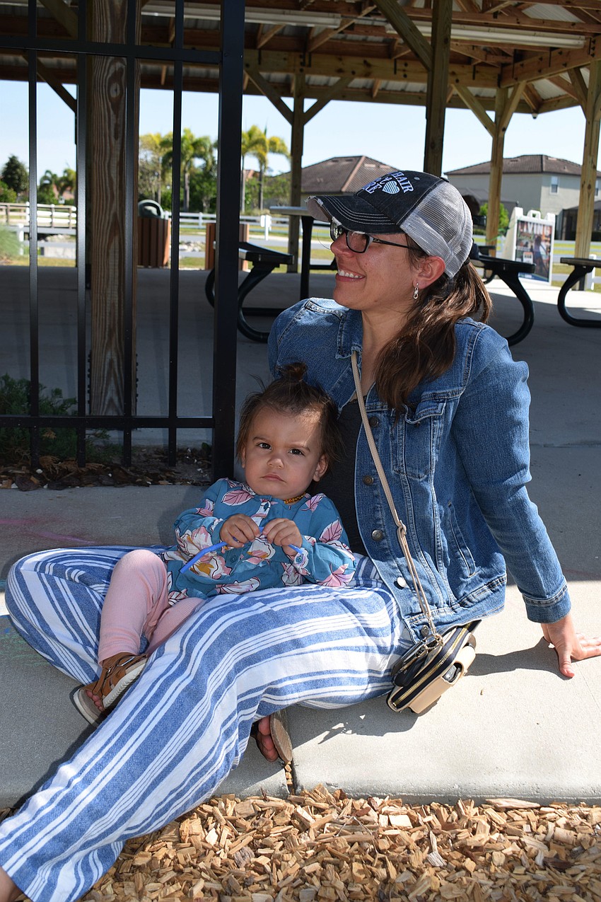 Parrish's Sadie Woods, who is 1, rests in her mother, Jessica Woods', lap before starting to play on the playground.