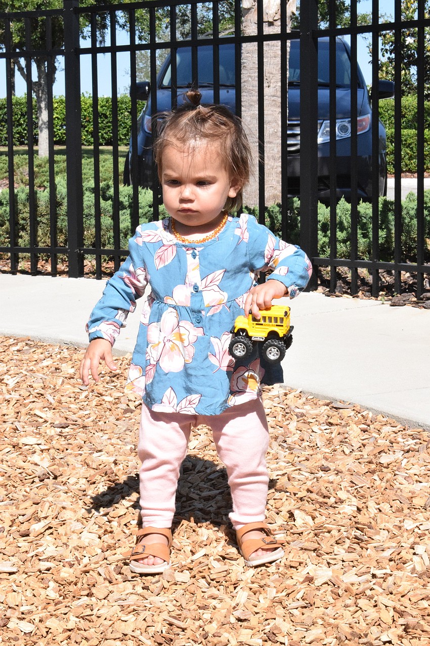 Parrish's Sadie Woods, who is 1, plays with toys while walking around the playground.