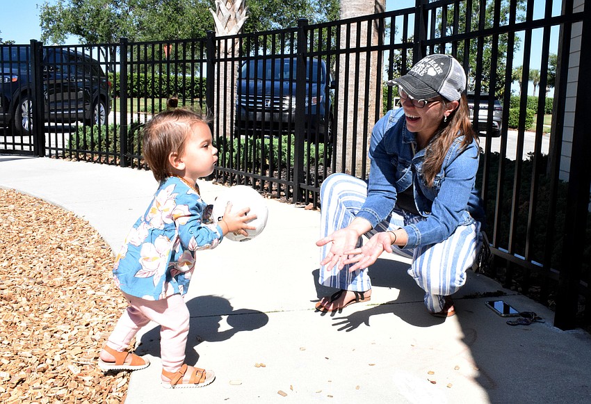 Parrish's Sadie Woods, who is 1, throws a ball while playing with her mother, Jessica Woods.