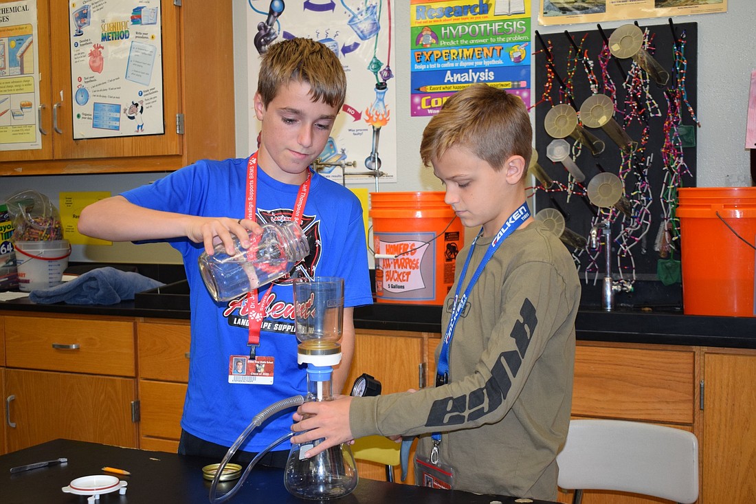 Braden River Middle School eighth grader Stephen Althoff pours water to be filtered as Griffin Hart holds the flask. Middle school students have an opportunity for credit recovery in core classes like science. File photo.