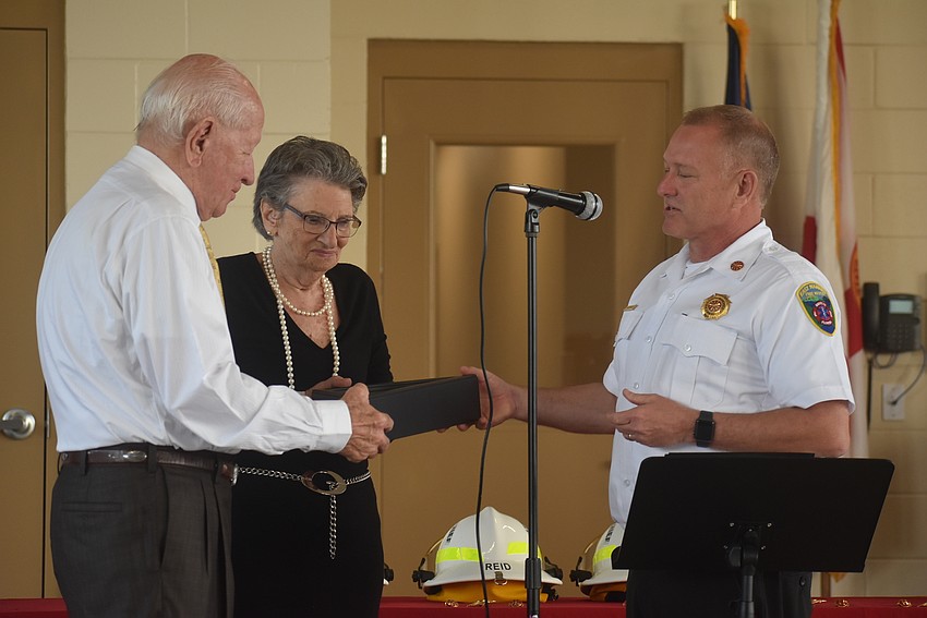 Former East Manatee Fire Rescue District Commissioner Don O'Leary and his wife, Audrey O'Leary, receive the first flag to ever fly over East Manatee Station 8 from East Manatee Fire Rescue District Chief Lee Whitehurst.