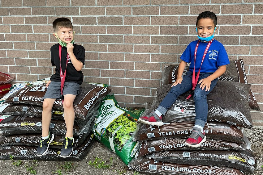 Michael Morena and Nathan Lopez Chang, kindergartners at Tara Elementary School, sit atop bags of soil the school was able to purchase using a $500 grant.