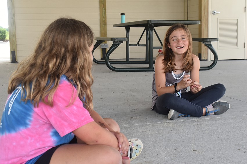 Greenbrook residents Nahla Vlasak, 9, and Ava Clementi, 8, laugh at the end of a story about a lion eating a mouse, which resulted in mice becoming extinct in Africa. The children created the story themselves one word at a time.