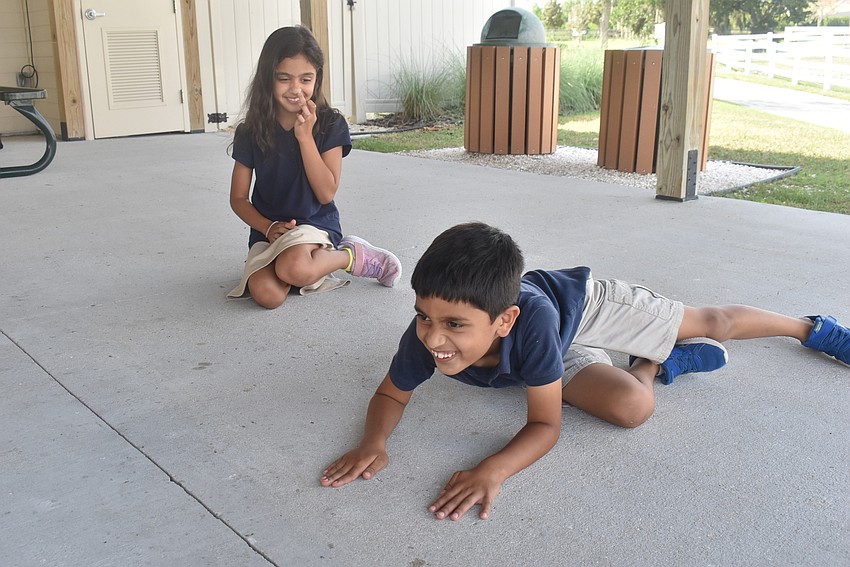 Bridgewater resident Adaa Chauhan, 9, laughs at her brother, Veer Chauhan, 7, as he pretends to be a naked mole rat as part of the game 