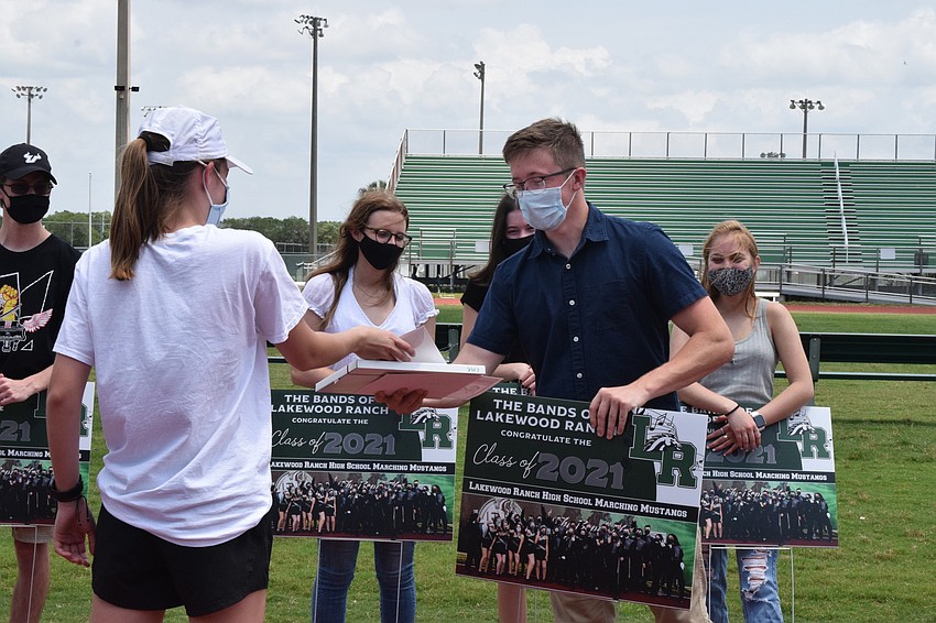 New drum major Maya Landers gives a certificate to senior Cole Nash.