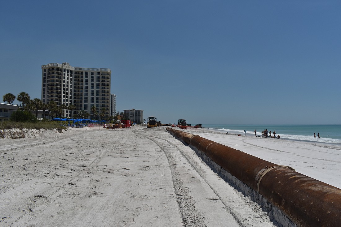 A dredging pipe stretches along the beach.